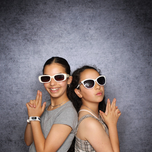 Two women wearing sunglasses against a dark gray background